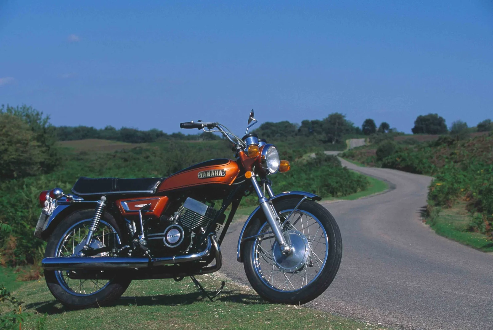 Yamaha RD350 clássica de dois tempos em azul com listras brancas, destacando seu design esportivo e atemporal.