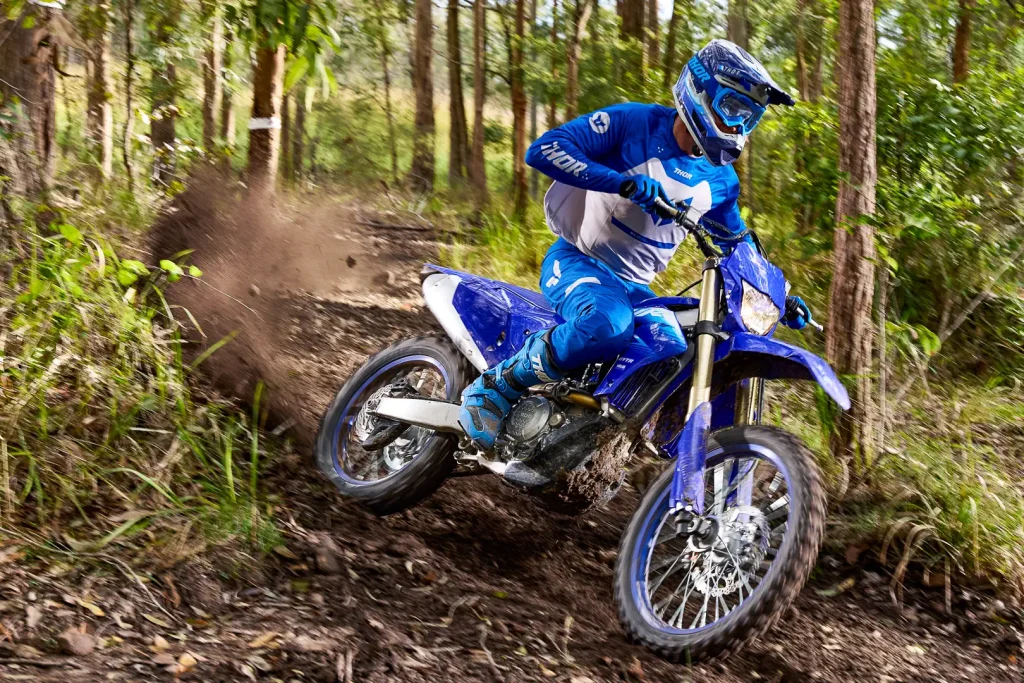 Yamaha WR450F 2027 azul em ação em trilha de terra com suspensão trabalhando