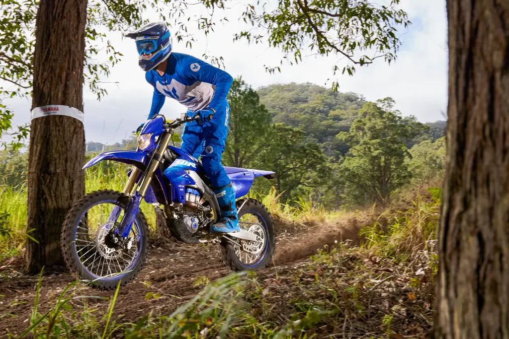 Yamaha WR450F 2027 azul em ação em trilha de terra com suspensão trabalhando