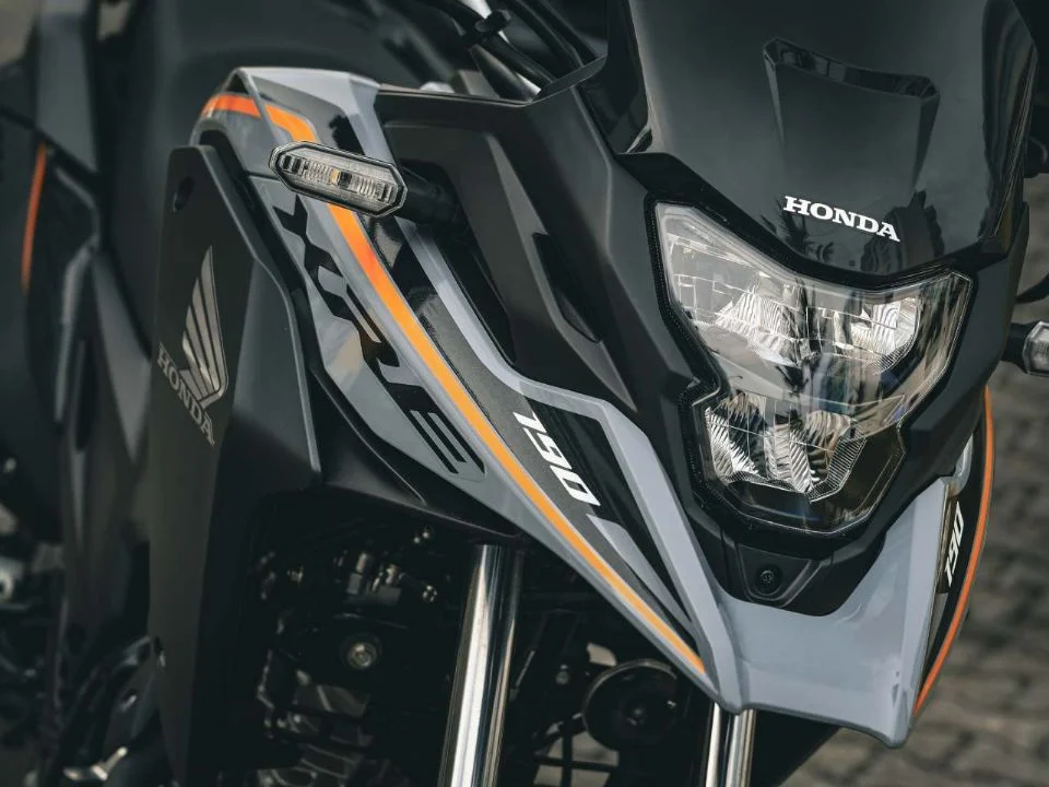 Honda XRE 190 2026 cinza metálico estacionada, exibindo o design atualizado com bico alongado e iluminação LED, destacando sua proposta trail.