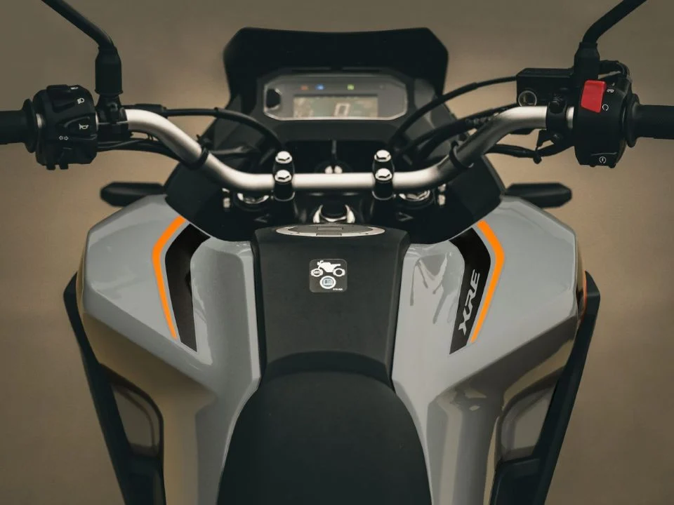 Honda XRE 190 2026 cinza metálico estacionada, exibindo o design atualizado com bico alongado e iluminação LED, destacando sua proposta trail.