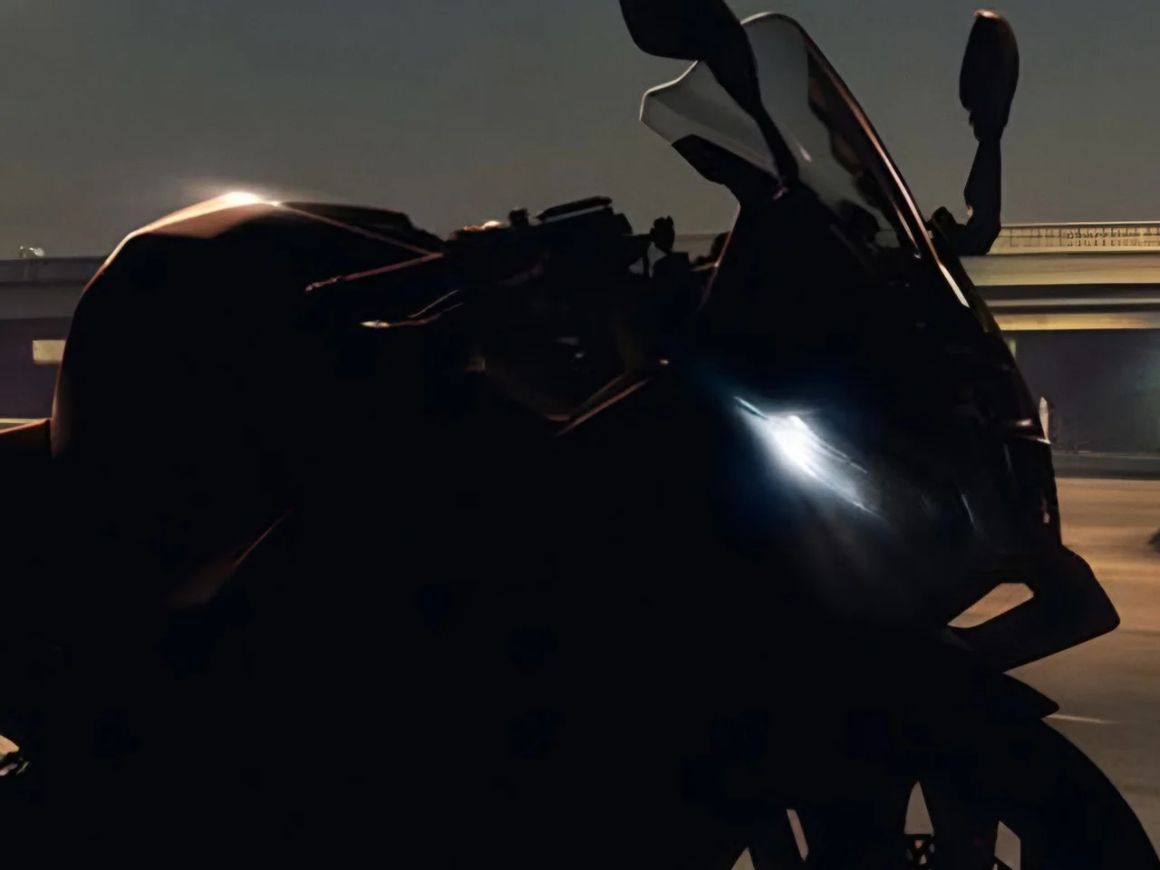 Silhueta sombreada de uma nova moto esportiva carenada divulgada em teaser oficial pela BMW Motorrad
