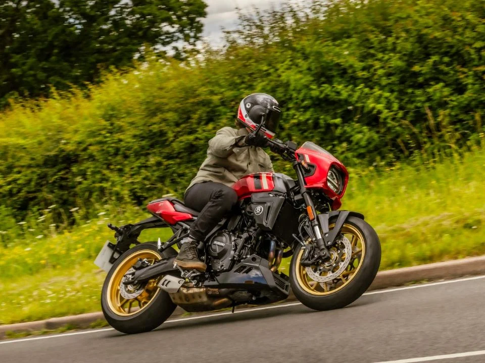 Suzuki GSX-8TT 2027 na nova cor Candy Daring Red, destacando o tanque vermelho com grafismos dourados, rodas douradas e carenagem frontal em estilo retrô.